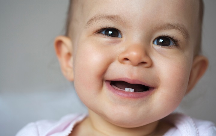 Baby smiling with two bottom teeth showing