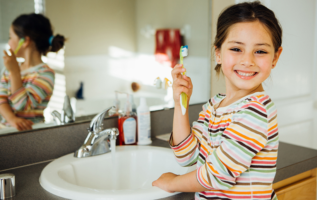 Kid brushing teeth at bathroom sink