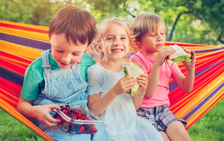 Kids on hammock having sandwiches and strawberries