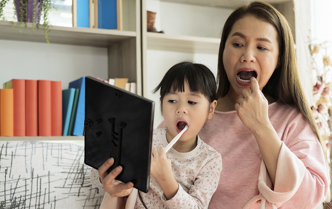 Mom with daughter learning to brush her teeth