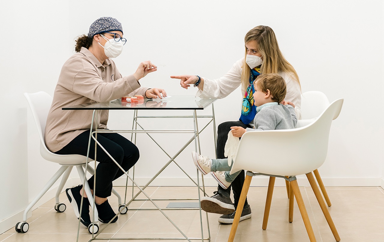 Photograph of a dentist speaking to a mother and her child
