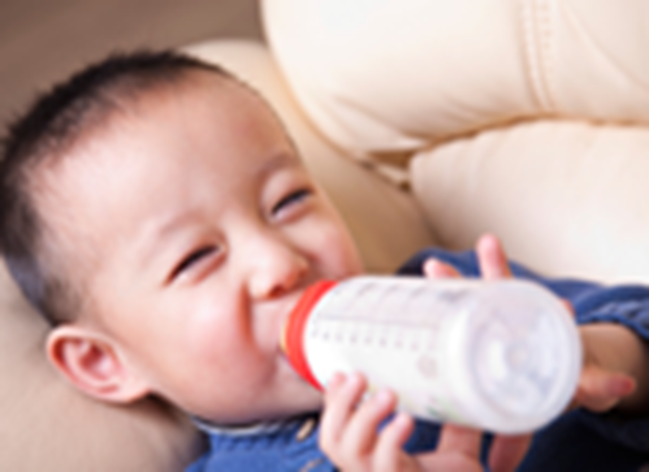 A photograph of a baby with a bottle.