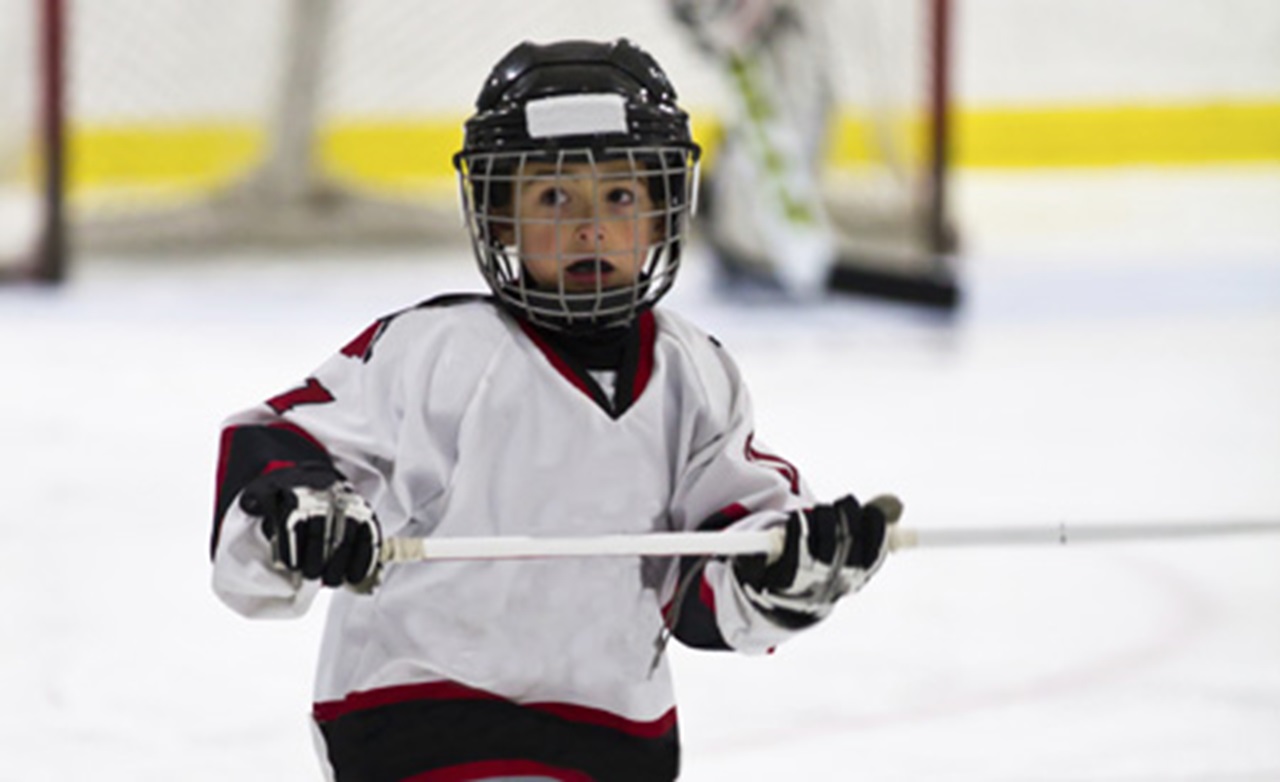 A child plays hockey while wearing a mouthguard.