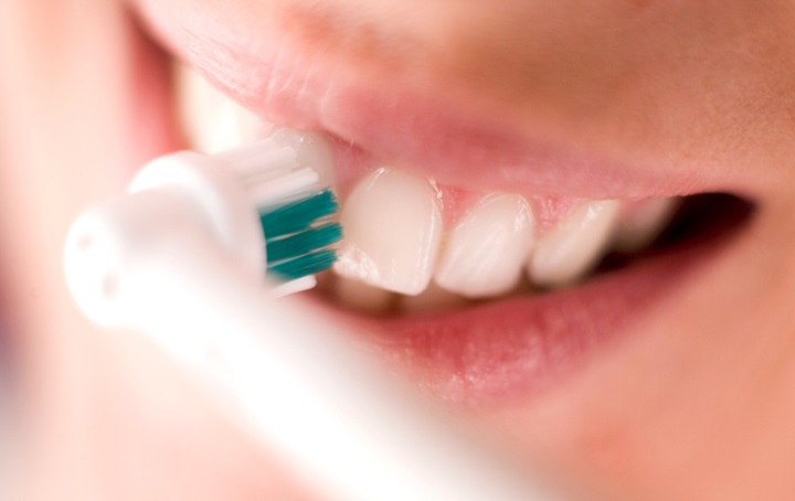 Closeup of brushing teeth with electric toothbrush