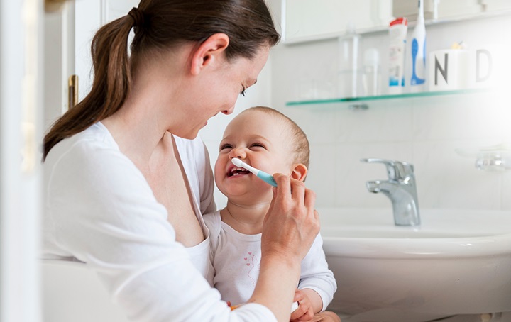Mother brushing baby's teeth
