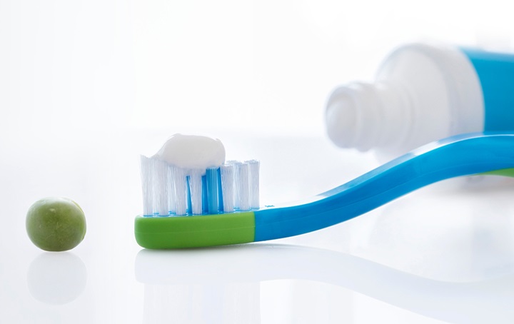 Pea, toothbrush with pea sized toothpaste on it, top of toothpaste tube