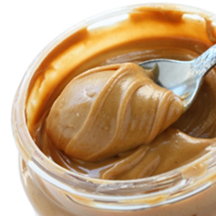 Open jar of peanut butter with spoon.