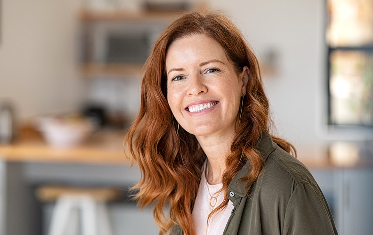 Female smiling with blurred kitchen image in the background.