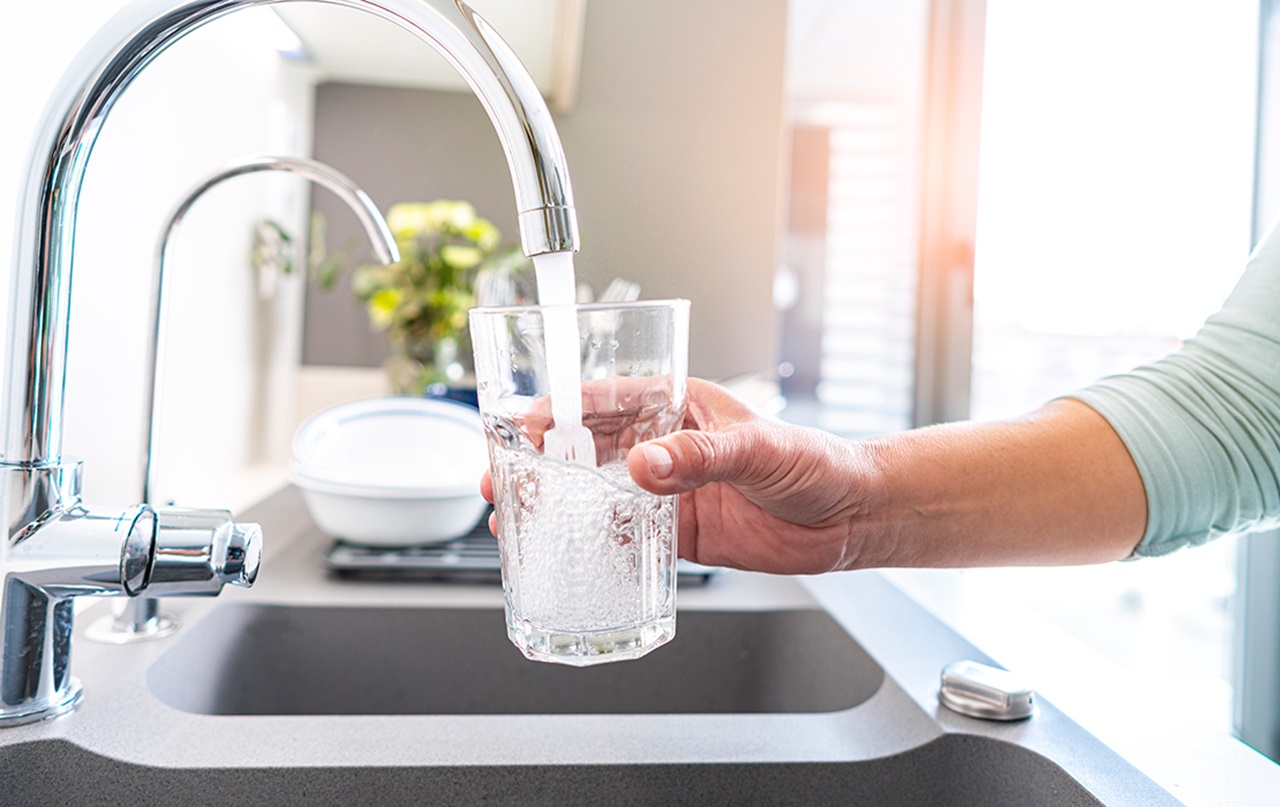 Mouthhealthy Person holding glass to fill with water at kitchen sink