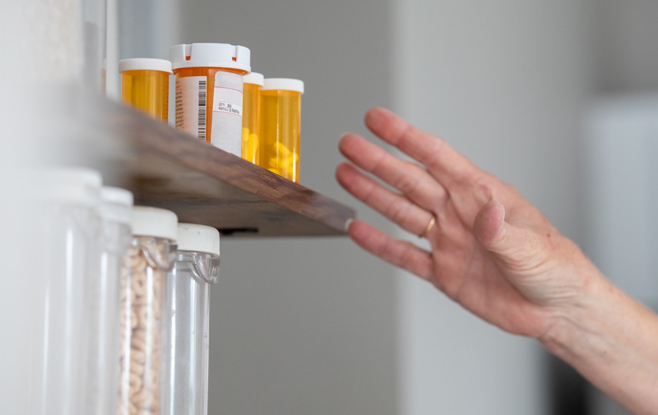 A person is reaching for a prescription bottle.
