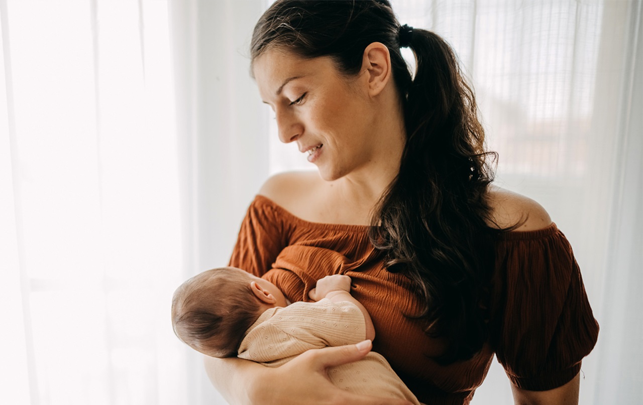 A mother staring down at her baby while she is brestfeeding.