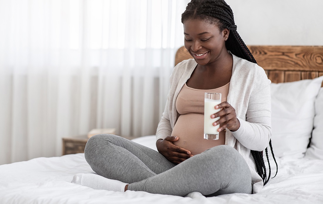Pregnant person sitting on a bed