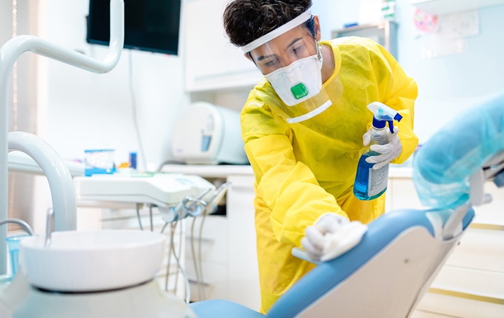 A person disinfecting a dental office chair