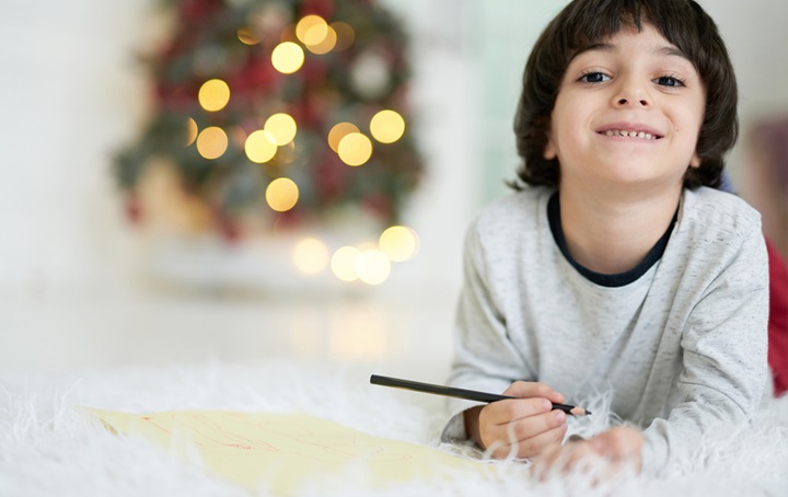 A young child, smiling and working on crafts for the holidays