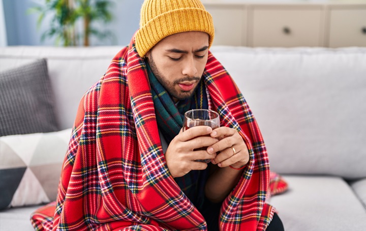 A sick male having a drink and trying to stay hydrated.