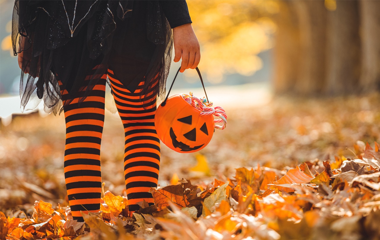 A child dressed for Halloween walking with a bucket
