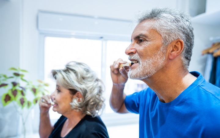 An older couple brushing their teeth together.