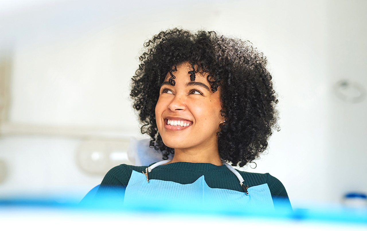 A photograph of a smiling woman at the dentist.