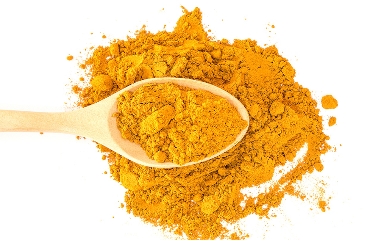 Ground Turmeric and wooden spoon.