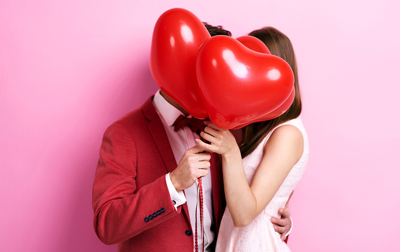MouthHealthy couple hiding behind two heart shaped balloons