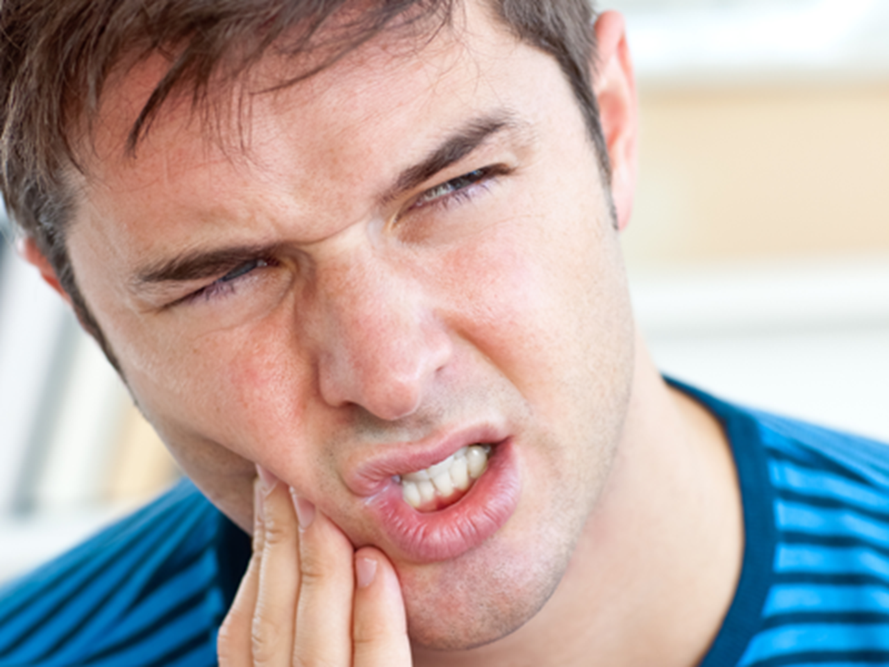 Young man grimacing with a toothache